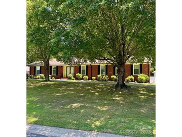 Charming brick home with black shutters and mature trees in the front yard at 8616 Fallsdale Dr, Charlotte, NC 28214