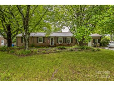 Charming brick home with green shutters, a well-manicured lawn, and mature trees at 1005 Fieldstone Rd, Mooresville, NC 28115