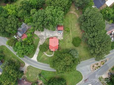 Stunning aerial view of a charming home with a bright red roof surrounded by lush greenery and mature trees at 1614 Linwood Rd, Gaston, NC 28052