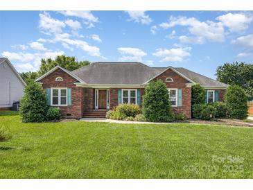 Charming red brick home featuring a well-manicured lawn, lovely landscaping, and appealing exterior design at 2627 Willis Dr, Harrisburg, NC 28075
