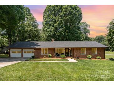 Charming brick home with an attached two-car garage, lush green lawn, and mature trees at 400 S Westover Dr, Monroe, NC 28112