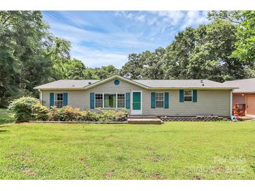 Charming single-story home with a well-maintained lawn, blue shutters, and mature trees in a serene, residential neighborhood at 4104 Pebblebrook Sw Cir, Concord, NC 28027