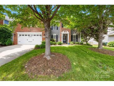Charming two-story home featuring a lush front yard, brick accents, and a welcoming entrance with a blue door at 622 Lorain Nw Ave, Concord, NC 28027