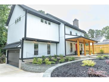 Beautiful white two-story home featuring a black roof, covered front porch, and manicured landscaping at 136 Digh Cir # 4, Mooresville, NC 28117
