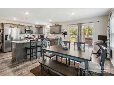 The kitchen features gray cabinets, stainless steel appliances, and an island with seating adjacent to the dining area at 3401 Shillinglaw Rd, Sharon, SC 29742