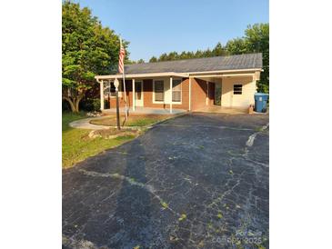 Charming brick home featuring a metal roof, attached carport, and well-maintained landscaping at 490 S Moose Rd, Mount Pleasant, NC 28124