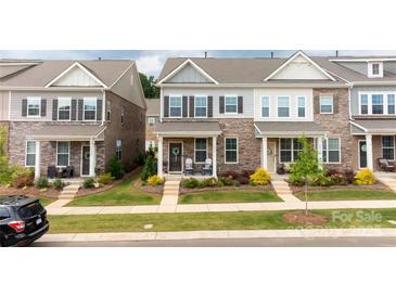 Charming townhome boasts a well-manicured lawn, flowering shrubbery, and covered front porch at 5440 Kinsbridge Dr, Charlotte, NC 28227