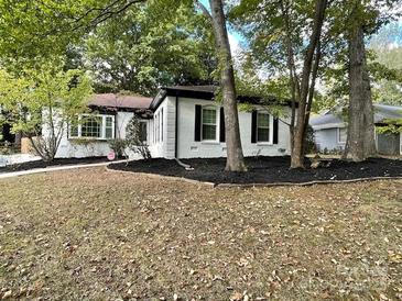 Charming single-story home featuring manicured landscaping and a classic design with black shutters and fresh mulch at 6128 Coatbridge Ln, Charlotte, NC 28212