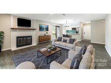 Comfortable living room with a fireplace, gray rug, and views into kitchen at 712 Mallard Head Ln, Mooresville, NC 28117