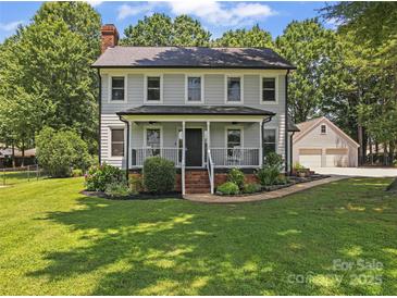Charming two-story home features a welcoming front porch, complemented by a well-manicured lawn and lush landscaping at 18733 Bluff Point Rd, Cornelius, NC 28031