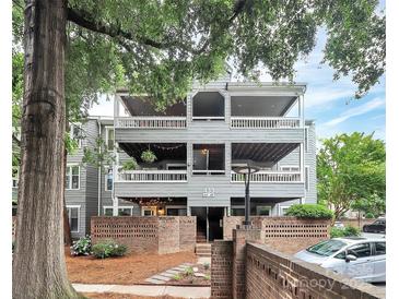 Multi-level condo building with balconies, brick accents, mature trees, and parking at 433 W 8Th Street St, Charlotte, NC 28202