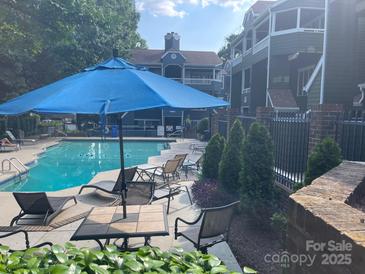 A luxurious community pool with lounge chairs, a dining table, and a bright blue umbrella for shade at 433 W 8Th Street St, Charlotte, NC 28202