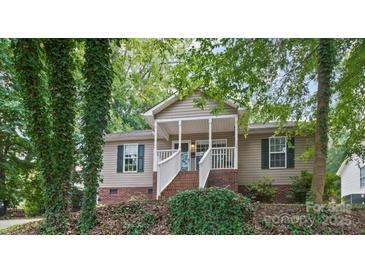 Charming home with a brick foundation, inviting front porch, and lush trees at 471 Hillandale Ne St, Concord, NC 28025