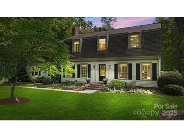 Charming two-story home featuring a lush green lawn, mature trees, and classic black shutters at 7213 Lancer Dr, Charlotte, NC 28226