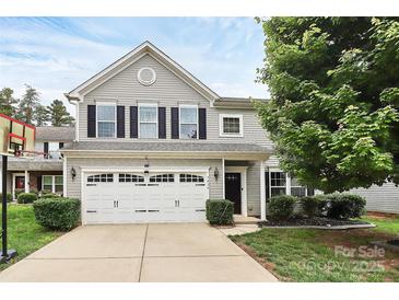 Charming two-story home featuring a two-car garage, complemented by a well-maintained front lawn and mature tree at 7434 Dover Mill Sw Ln, Concord, NC 28025