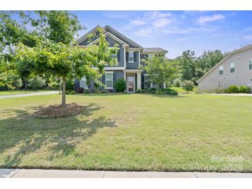 Charming two-story home boasts lush green lawn and mature trees in a well-maintained front yard at 8340 Breton Way, Harrisburg, NC 28075