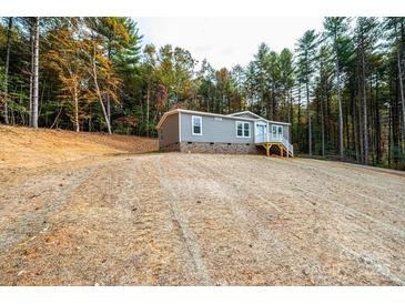 Attractive gray home with white trim, nestled amongst mature trees, offers a serene and private setting at 122 River Ridge Ln, Hickory, NC 28601