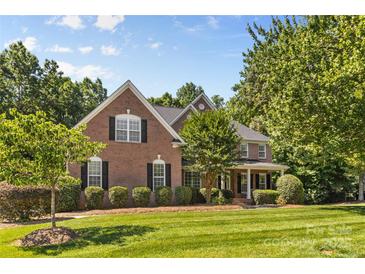 Beautiful two-story brick home with a manicured lawn and mature trees on a sunny day at 1336 Dobson Dr, Waxhaw, NC 28173
