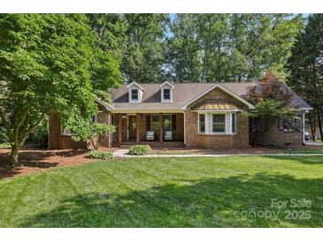 Charming brick home with a manicured lawn, covered porch, and mature trees at 10311 Windtree Ln, Charlotte, NC 28215