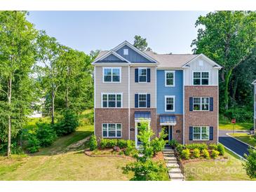 Charming townhome featuring brick accents, complemented by lush green landscaping, and dark shutters at 12024 John Newton Dr, Davidson, NC 28036