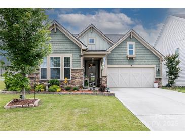 Charming home featuring stone accents, well-manicured lawn, flower beds, and a two-car garage at 132 Hillston Ln, Mooresville, NC 28115