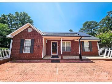 Charming brick home featuring a brick driveway, well-manicured lawn, and welcoming front porch at 501 N Johnson St, Monroe, NC 28112