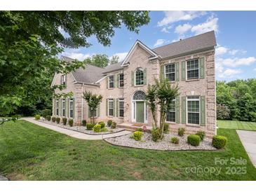 Stunning two-story brick home featuring a manicured lawn and complemented by lush, mature trees at 4201 Amber Leigh Way Dr, Charlotte, NC 28269