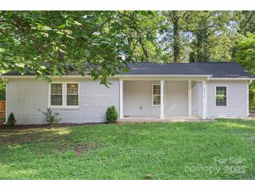 Charming single-story home with a brick facade and a cozy front porch, surrounded by lush greenery and a well-maintained lawn at 4410 Burgin St, Kannapolis, NC 28081