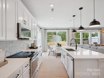 Bright modern kitchen with white cabinets, stainless appliances, and breakfast nook with backyard views at 502 Webster Ln, Cramerton, NC 28032
