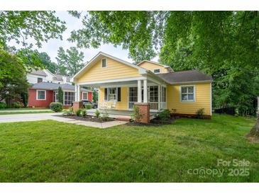 Charming yellow home boasts a welcoming front porch, lush lawn, and inviting curb appeal at 660 Ideal Way, Charlotte, NC 28203
