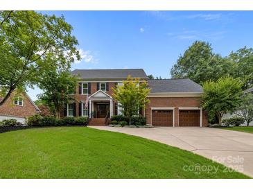 Beautiful brick home with a manicured lawn, mature trees, and a two-car garage at 6916 Cameron Glen Dr, Charlotte, NC 28210
