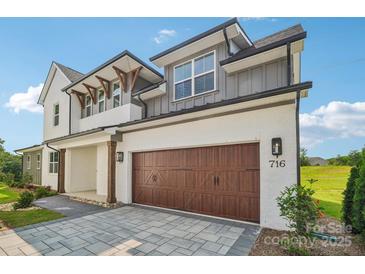 Modern two-story home with a stylish white and gray exterior and a brown wood garage door at 716 Flare Dr, Tega Cay, SC 29708
