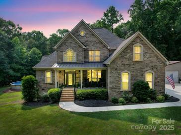 Charming brick home featuring a manicured lawn, inviting front porch, and professional landscaping at 8101 Cane Pointe Ln, Waxhaw, NC 28173