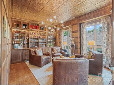 Incredible living room with tin ceilings, custom bar, and leather chairs for the ultimate entertaining experience at 1172 Queens Rd, Charlotte, NC 28207