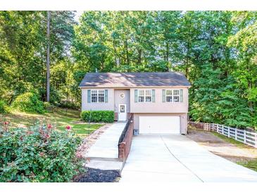 Charming two-story home with a well-manicured lawn, attached garage, and inviting front entrance surrounded by mature trees at 125 Shenandoah Loop, Troutman, NC 28166