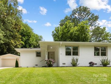 Charming single-story home with a white painted brick exterior, lush lawn, and a detached garage at 4929 Prentice Pl, Charlotte, NC 28210