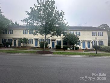 A row of charming townhomes featuring blue doors and shutters, enhanced by lush greenery at 5623 Fetzer Nw Ave, Concord, NC 28027