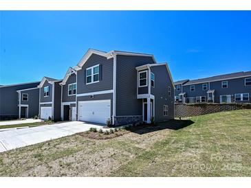 Modern townhome exterior with gray siding, white trim, and an attached garage on a sunny day at 7028 Alva Ter, Charlotte, NC 28216