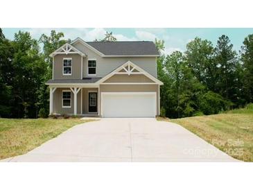 Charming two-story home features a two-car garage and neutral siding, set against a backdrop of lush trees at 7601 Hammond Dr, Charlotte, NC 28215