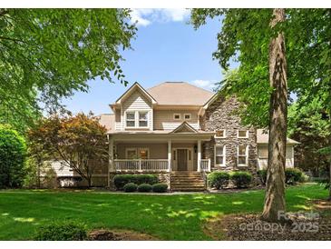 Charming two-story home with a stone and siding exterior, a welcoming front porch, and manicured landscaping at 8433 Cheverny Dr, Waxhaw, NC 28173