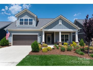Charming two-story home featuring gray siding, a covered porch, manicured landscaping, and a two-car garage at 1006 Gradison Dr, Matthews, NC 28104