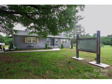 Charming gray brick home featuring a well-manicured lawn, shuttered windows, and inviting curb appeal at 1028 Washburn Switch Rd, Shelby, NC 28150