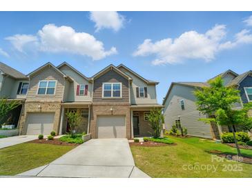 Inviting two-story townhome featuring a one-car garage, brick accents, and landscaped front yard at 5334 Orchid Bloom Dr, Fort Mill, SC 29707