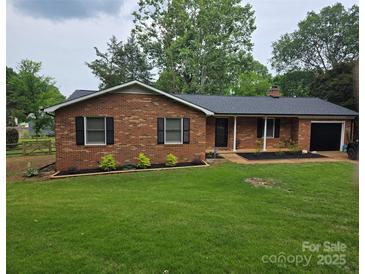 Charming single-story brick home featuring a well-manicured lawn and attached garage at 1713 Andover Nw St, Concord, NC 28027