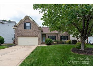 Charming brick home featuring a well-maintained lawn, mature trees, and attached two-car garage at 1003 Grayscroft Dr, Waxhaw, NC 28173