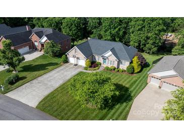 Charming brick home with a well-manicured lawn, lush landscaping, and a long driveway leading to the garage at 179 Browning Dr, Taylorsville, NC 28681