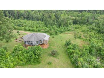 Aerial view of gray home with surrounding lawn and a mix of dense trees at 147 Buck And Doe Ln, Statesville, NC 28625