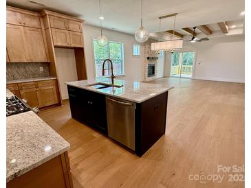 Open kitchen and living area featuring granite counters, stainless appliances, wood floors, and fireplace at 1721 S New Hope Rd, Gastonia, NC 28054