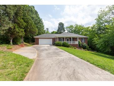 Charming brick home with a welcoming front porch and long driveway, surrounded by mature trees at 328 Burrage Ne Rd, Concord, NC 28025