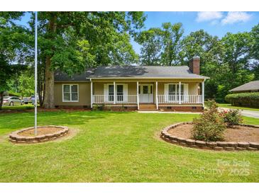 Charming single-story home with a well-manicured lawn, garden beds, and inviting front porch at 336 Oakwood Dr, Mount Holly, NC 28120